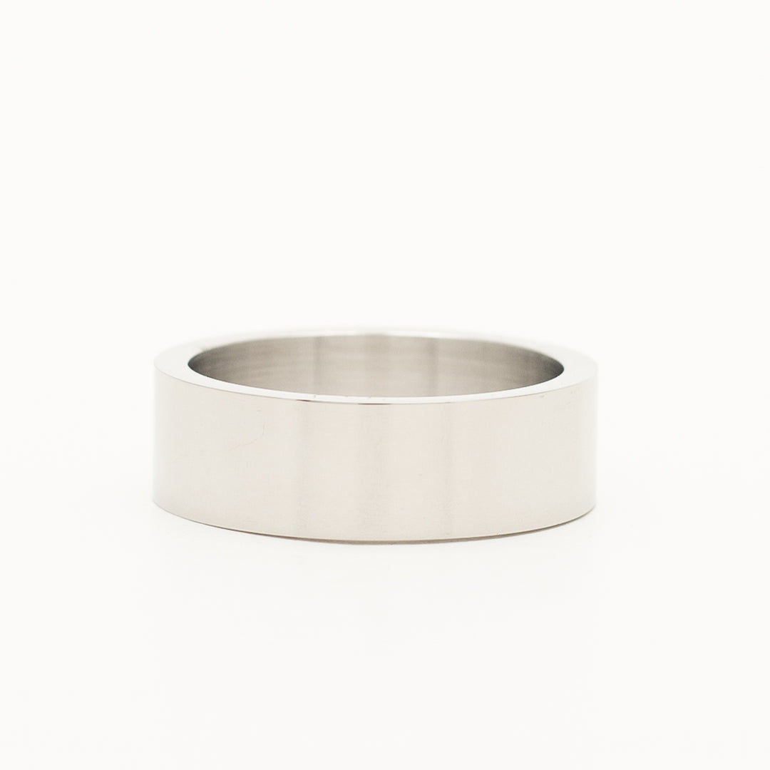 a ring in stainless steel is laying on the white table
