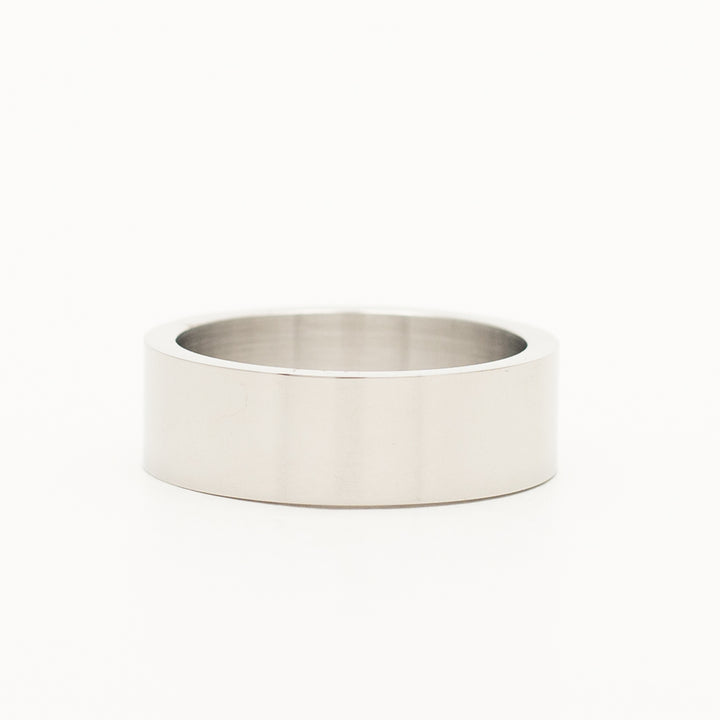a ring in stainless steel is laying on the white table