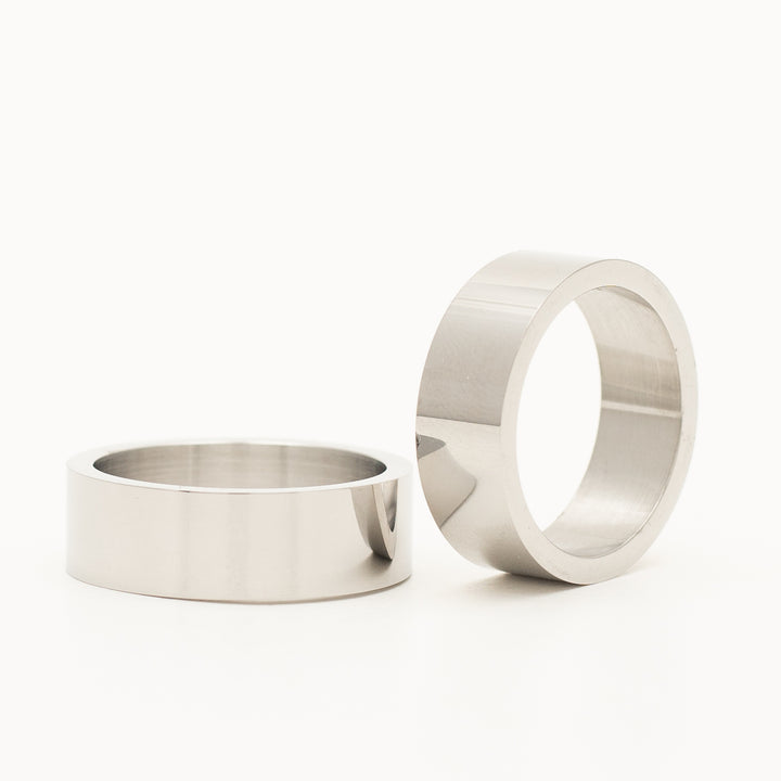 a ring in stainless steel is laying on the white table