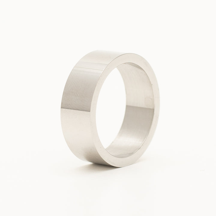 a ring in stainless steel is laying on the white table