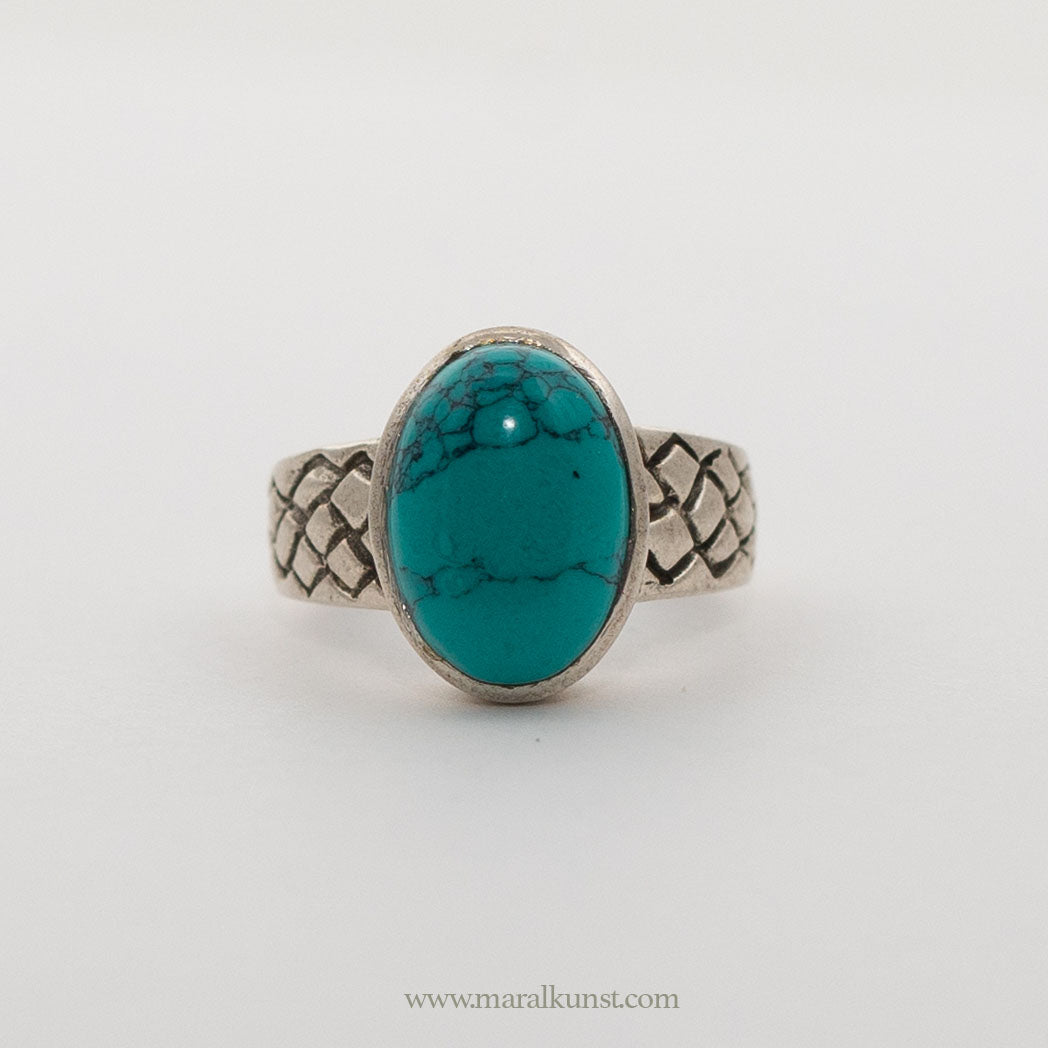 a turquoise ring in sterling silver is laying on the white table