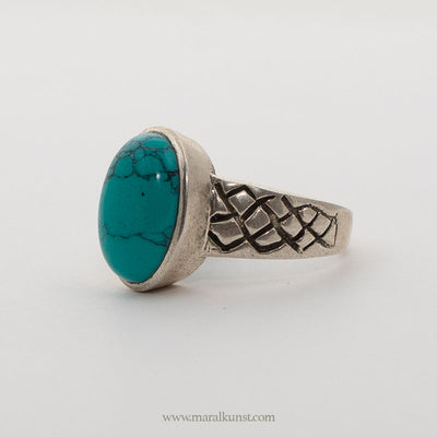 a turquoise ring in sterling silver is laying on the white table